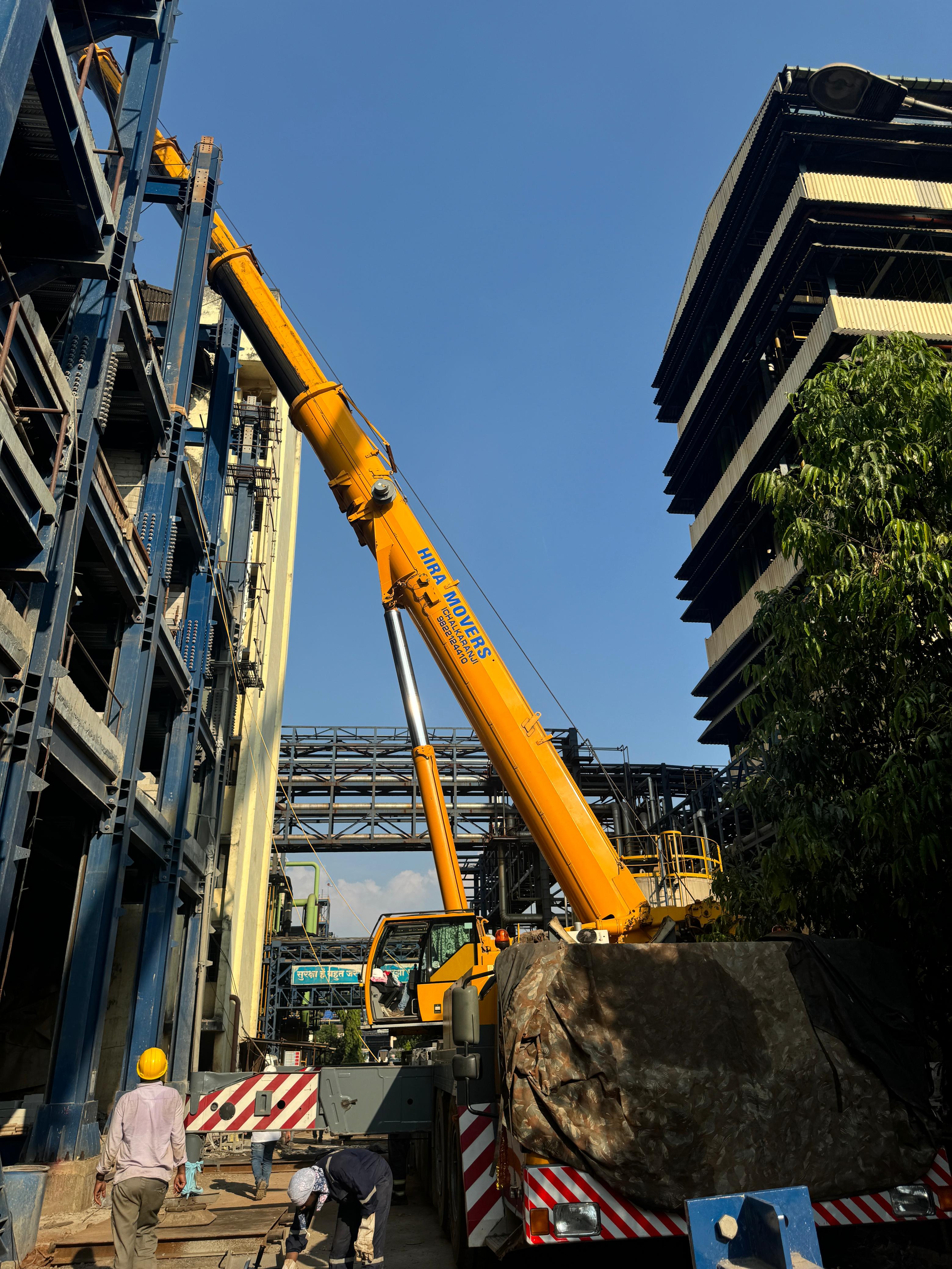 Hira Movers crane working between industrial buildings